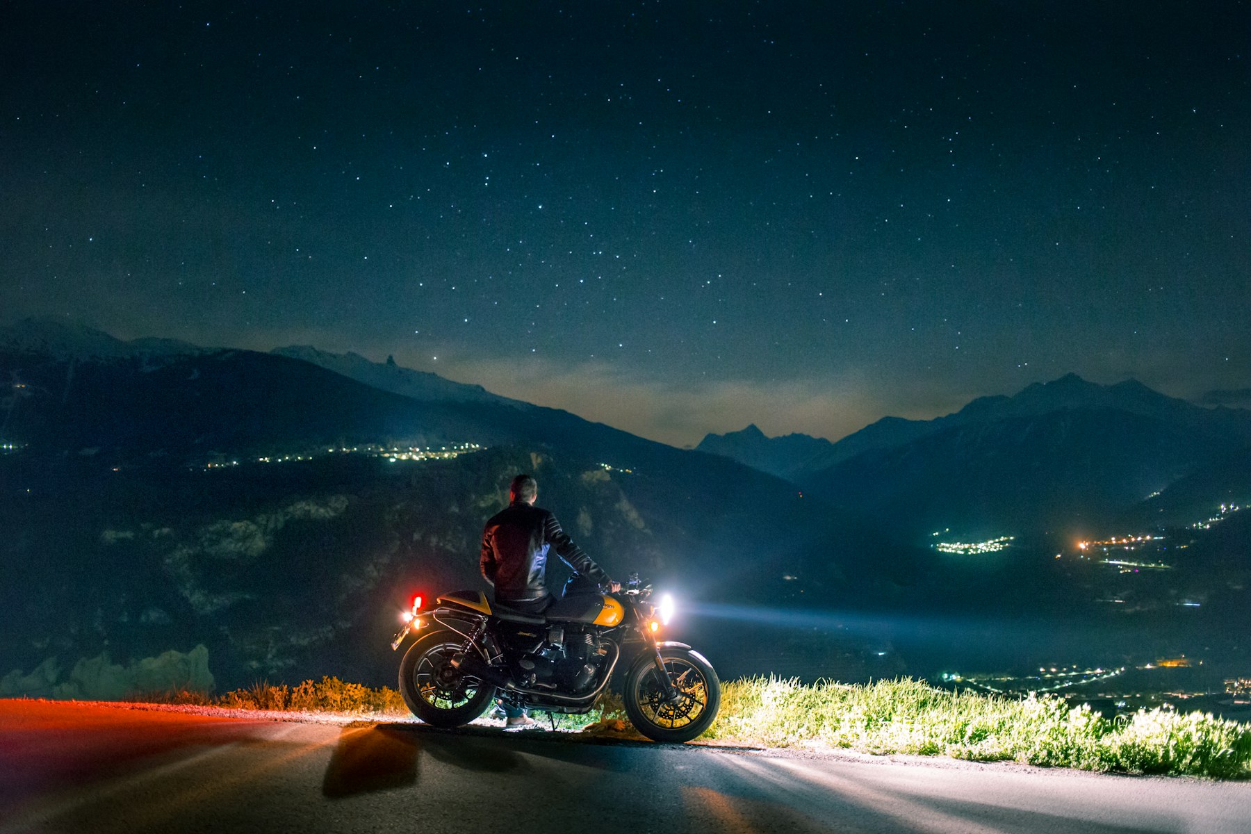 Motard face aux montagnes sous un ciel étoilé